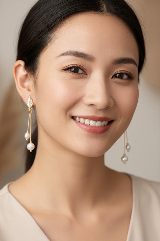 Pair of gold earrings with pearl drops on a white background