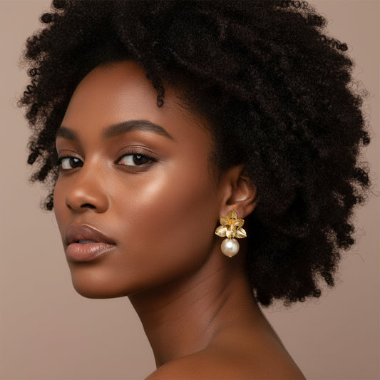 A pair of gold flower earrings with pearl drops, displayed against a neutral background.