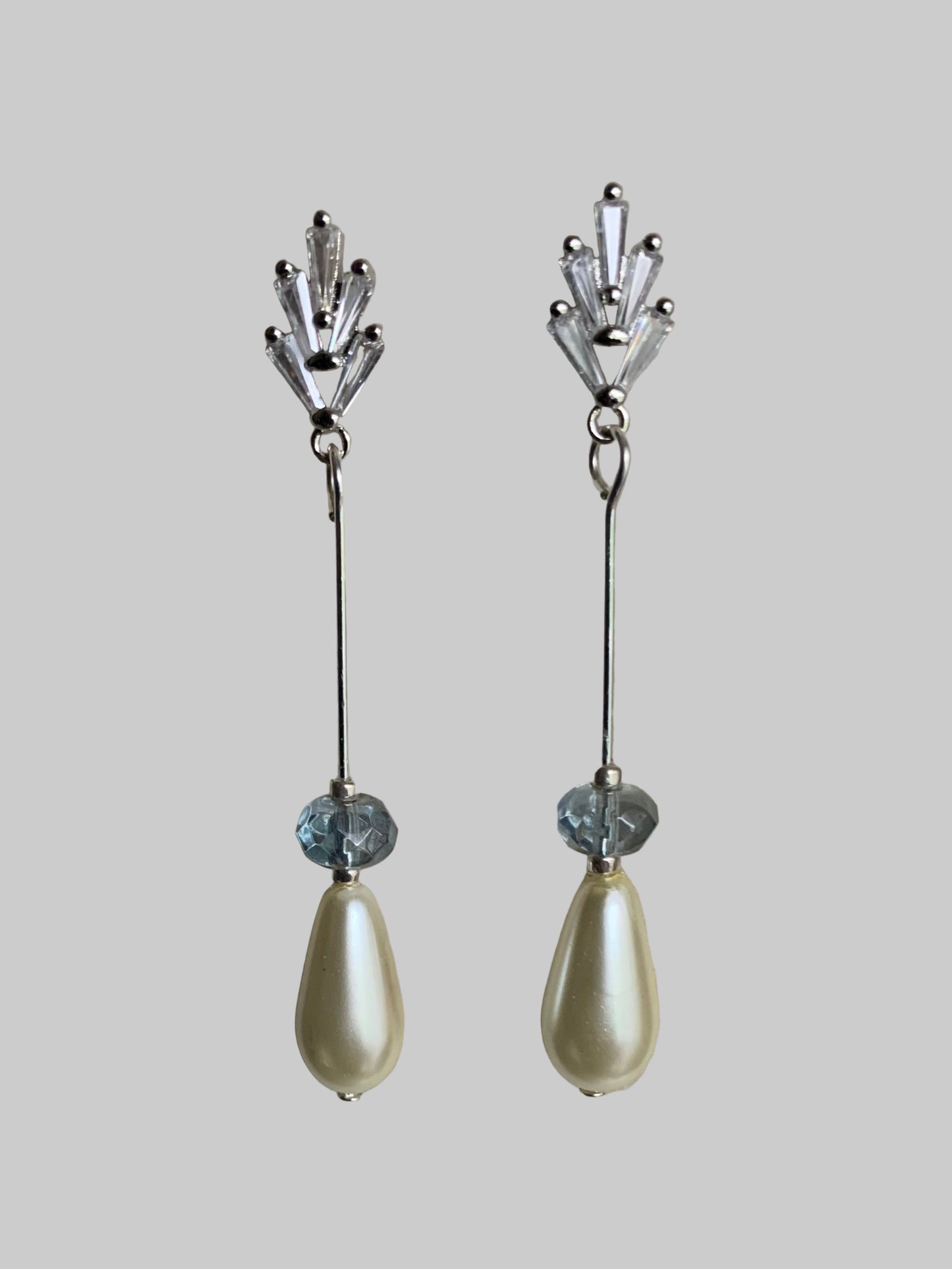 CZ earrings with teardrop pearl and blue crystal accents on neutral background.