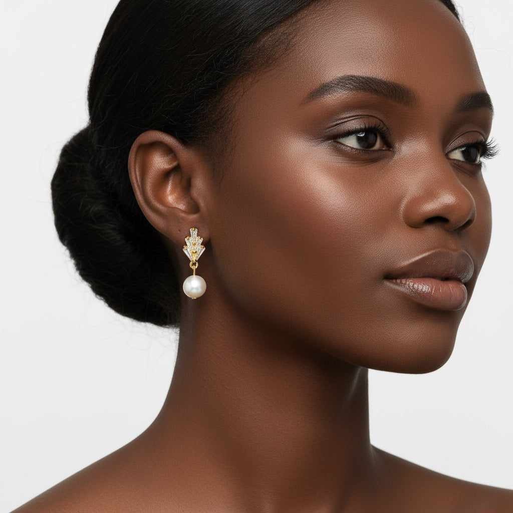 Pair of gold earrings with pearl drops on a light gray background