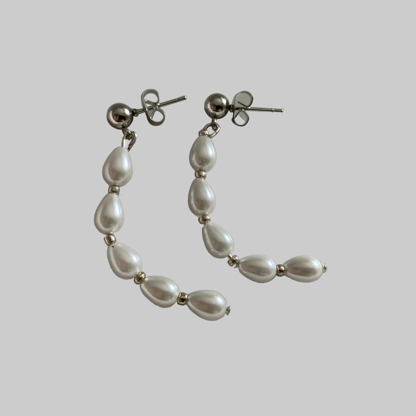 A pair of half circle teardrop pearl earrings with silver bead accents