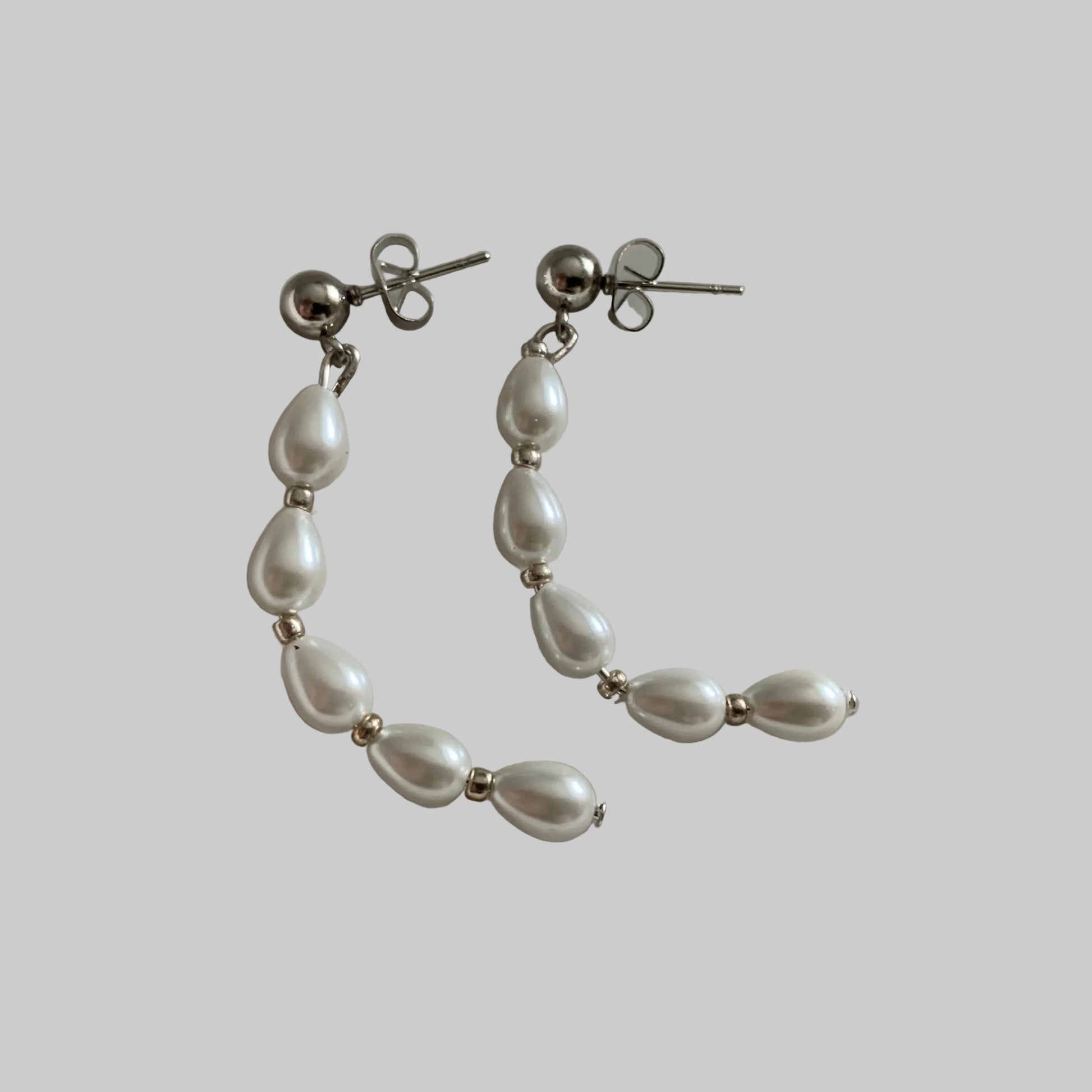 A pair of half circle teardrop pearl earrings with silver bead accents