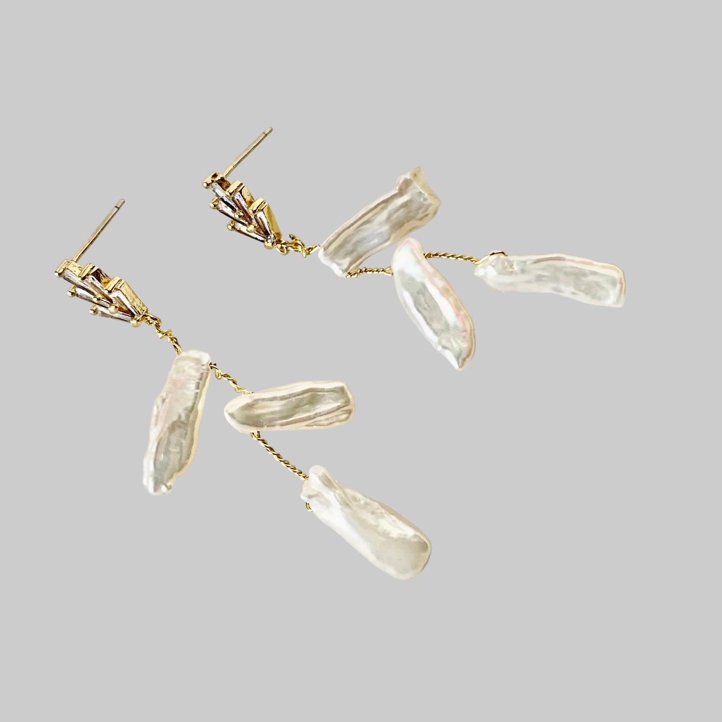 A pair of 18K gold plated Art Deco CZ triple biwa pearl earrings displayed against a white background.