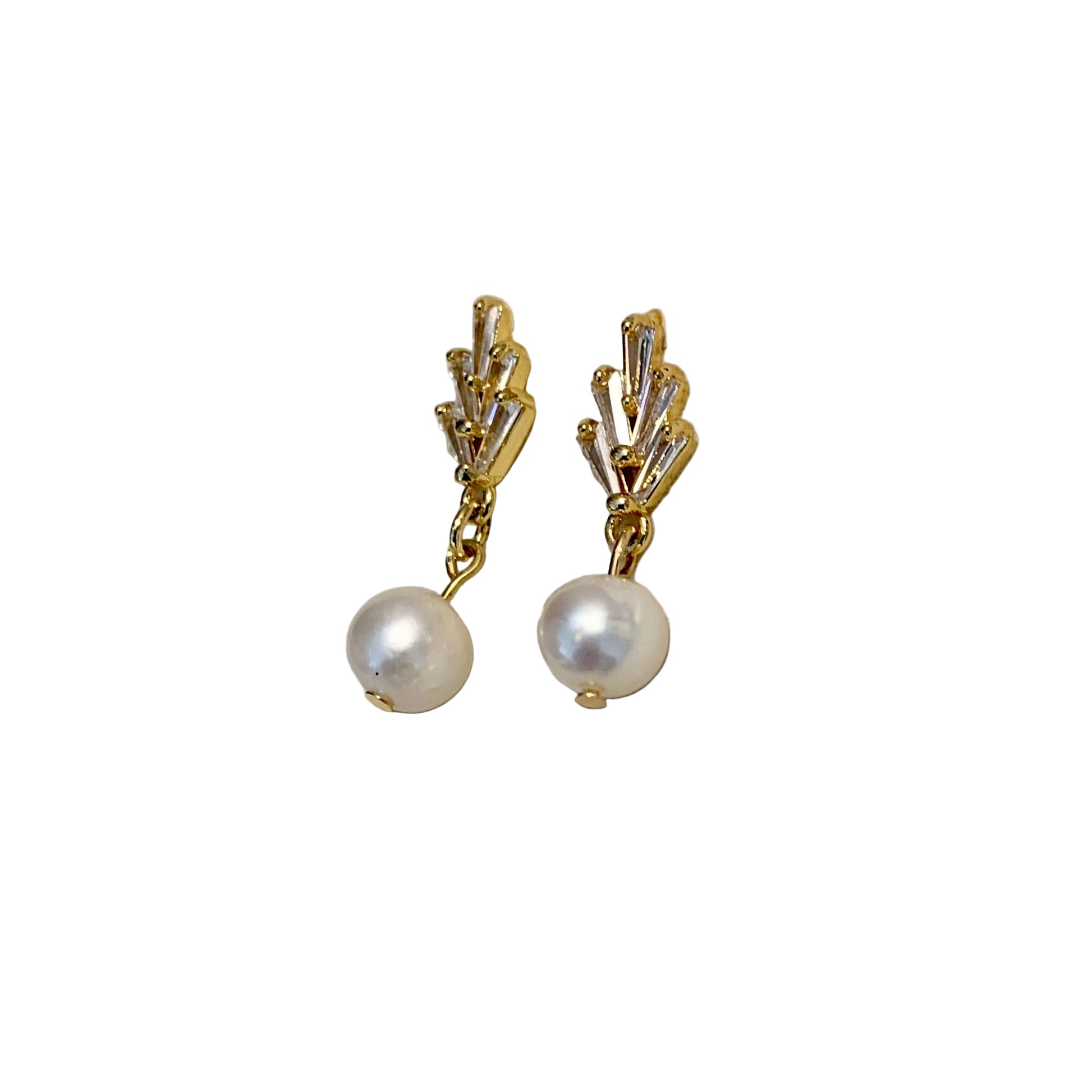 Gold earrings with pearl drops on a beige background