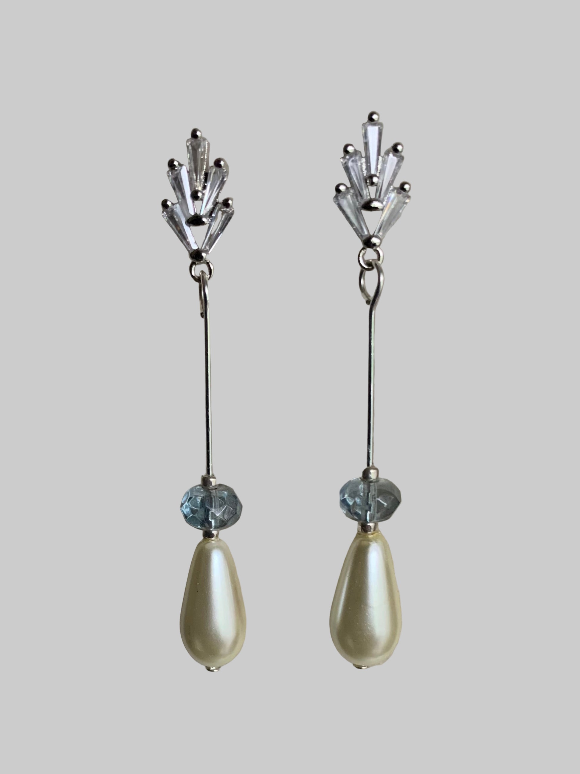 CZ earrings with teardrop pearl and blue crystal accents on neutral background.