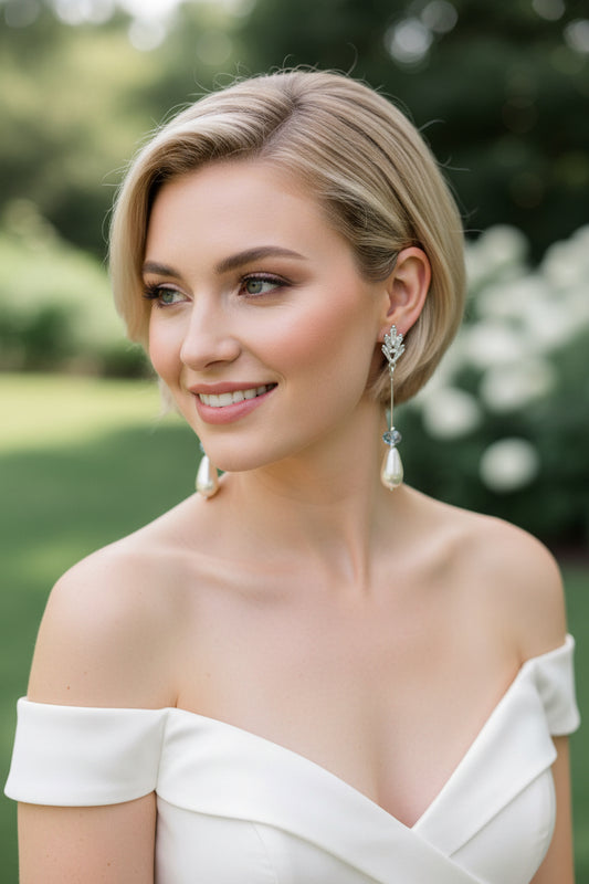 CZ earrings with teardrop pearl and blue crystal accents on neutral background.