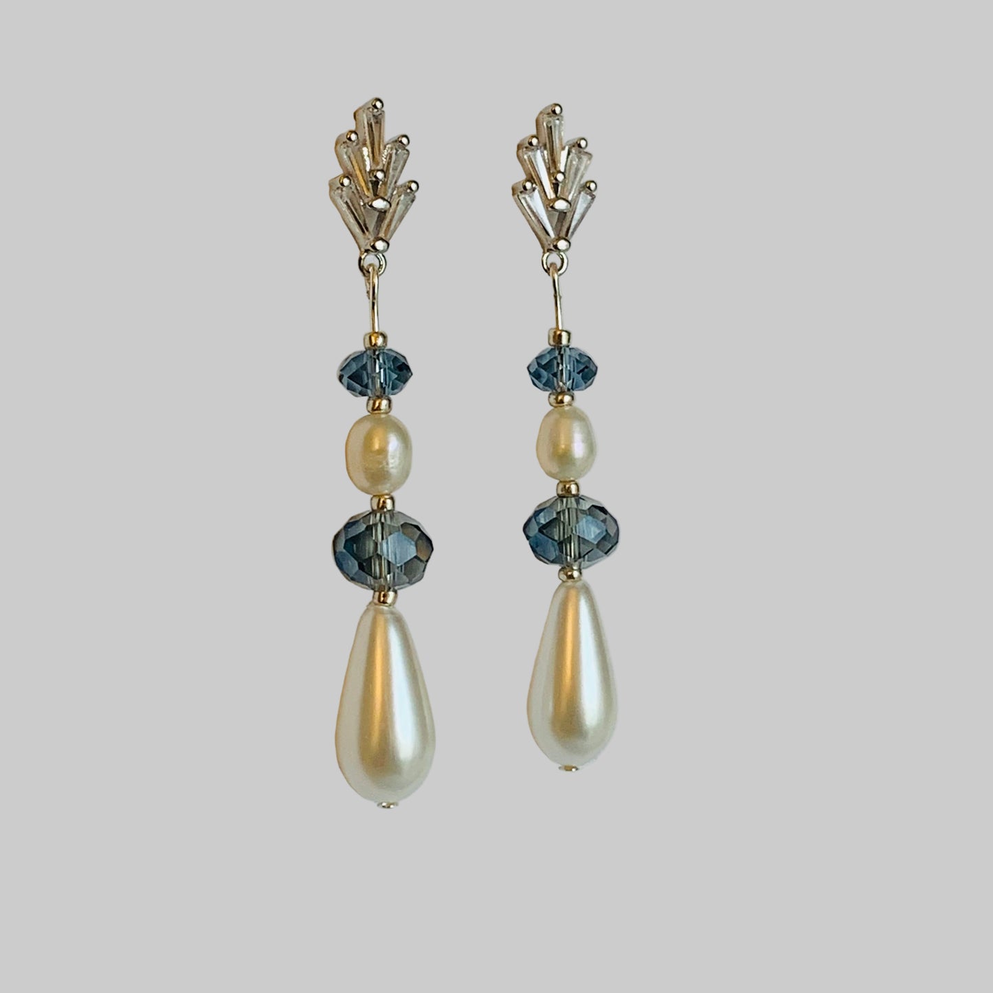 Pair of earrings with pearls and blue stones on a light gray background
